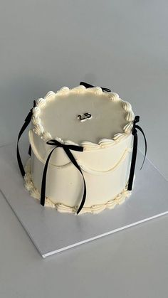 a white cake sitting on top of a silver plate with black ribbon around the edges