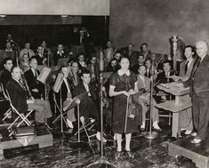 an old black and white photo of people in front of microphones with music instruments