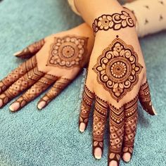 a woman's hand with henna tattoos on it, sitting on a blue towel