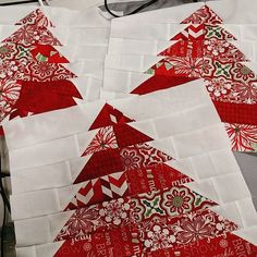 three red and white christmas trees made out of quilted fabric on a table top