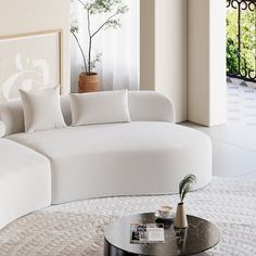 a living room with a large white couch and coffee table in front of the window