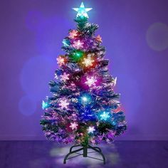 a brightly lit christmas tree in front of a purple background with stars on the top