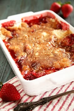 a close up of a casserole dish on a table with strawberries next to it