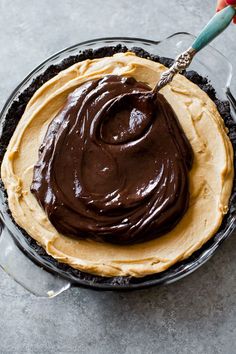 a pie with chocolate frosting on top in a glass pie dish, ready to be eaten