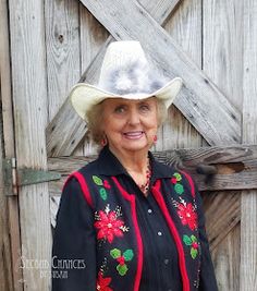 an older woman wearing a cowboy hat standing in front of a wooden fence with her hands on her hips