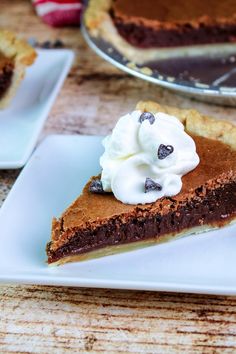 a slice of chocolate pie with whipped cream on top sits on a plate next to the rest of the pie