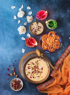 an overhead view of food on a blue surface with bowls and spoons next to it