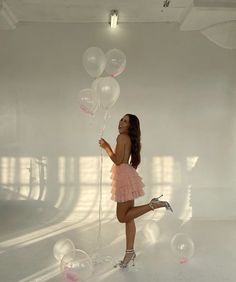 a girl in a pink dress is holding some balloons