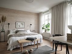 a bedroom with wood paneling, white bedding and wooden floors is pictured in this image