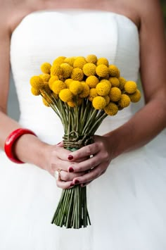 a bride holding a bouquet of yellow flowers