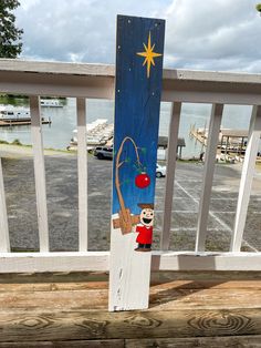 a wooden sign with a bear holding a cherry on it's back and a star above the top