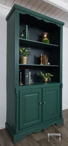 a green bookcase with potted plants on top