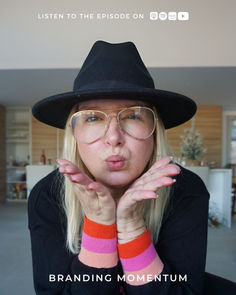 a woman wearing glasses and a black hat making a funny face with her hands in front of her face