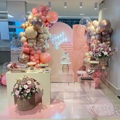 balloons and flowers are on display in the lobby at a birthday party with pink, gold and white decorations