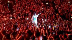 a man standing on top of a stage surrounded by lots of people holding up cell phones