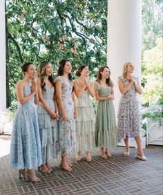 a group of women standing next to each other on top of a brick floor covered porch