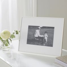 an old photo is sitting on a table next to a vase with flowers and books