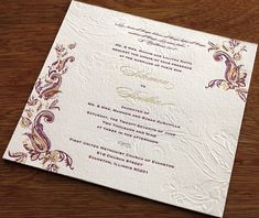 an ornate wedding card on a wooden table