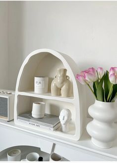 a white shelf with vases and candles on it