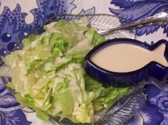 a salad with dressing in a bowl on a blue and white tablecloth