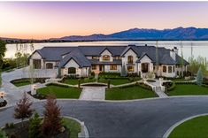 an aerial view of a large home in front of a lake with mountains in the background