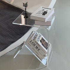 a glass table with two books on it and a candle holder sitting next to it