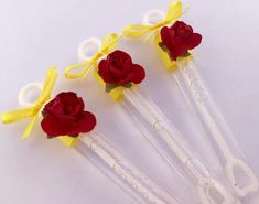 four plastic roses with yellow ribbon on them sitting next to each other in front of a white background