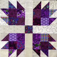 a close up view of a quilted patchwork design with purple and white colors