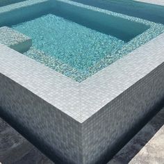 an empty swimming pool in the middle of a tiled floored area with blue water