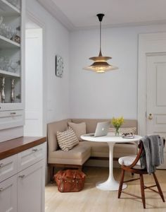 a kitchen with white walls and wooden floors, an l - shaped table in the center