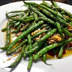 a white plate topped with green beans covered in sauce and seasoning on top of it