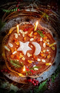 a cake decorated with candles and nuts on top of a platter filled with berries