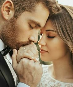 a man and woman holding each other close to their foreheads as they look at each other