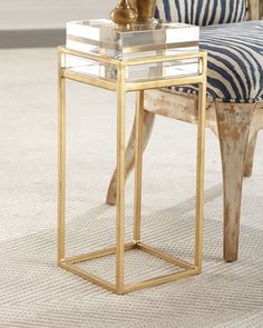 a zebra print chair sits next to a glass table with a gold vase on top