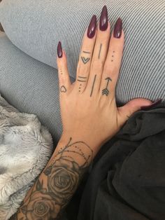 a woman's hand with tattoos on it and her left hand resting on the couch