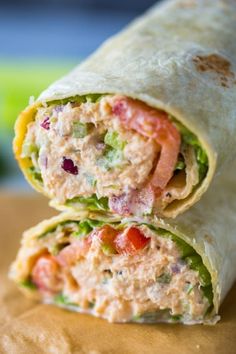 a wrap filled with meat and veggies sitting on top of a table