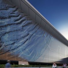 people are walking near a large building with glass covering it