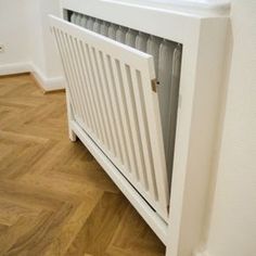 a white radiator sitting on top of a wooden floor next to a wall