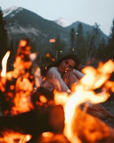 a woman sitting in front of a campfire