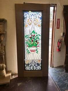 a stained glass door with flowers on it in a room next to a stone statue