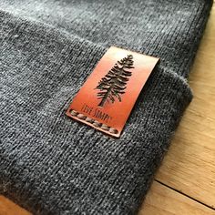 a brown leather tag on a gray sweater with a tree patch in the front and back