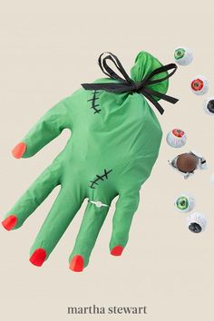 a green hand that has been decorated with black and red nail polish