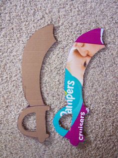 a pair of scissors cut out from cardboard on the floor next to an advertisement