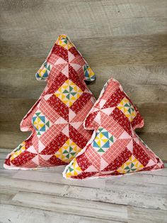 two red and yellow christmas trees sitting on top of a wooden table next to each other