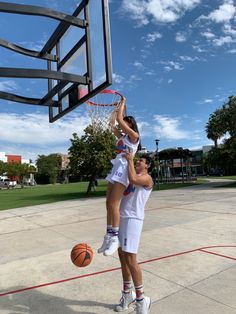 two people playing basketball on a court with the sky in the backgrouds