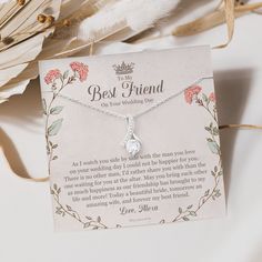 the best friend necklace is on display next to some feathers and flowers, with a card attached