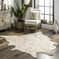 a living room with wooden floors and white rugs on the floor next to a window