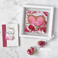 two valentine's day cards in a white frame on a marble surface with pink flowers