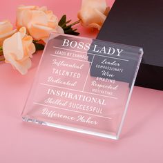 a glass plaque with the words boss lady on it next to some flowers and a black box