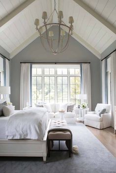 a bedroom with white furniture and large windows